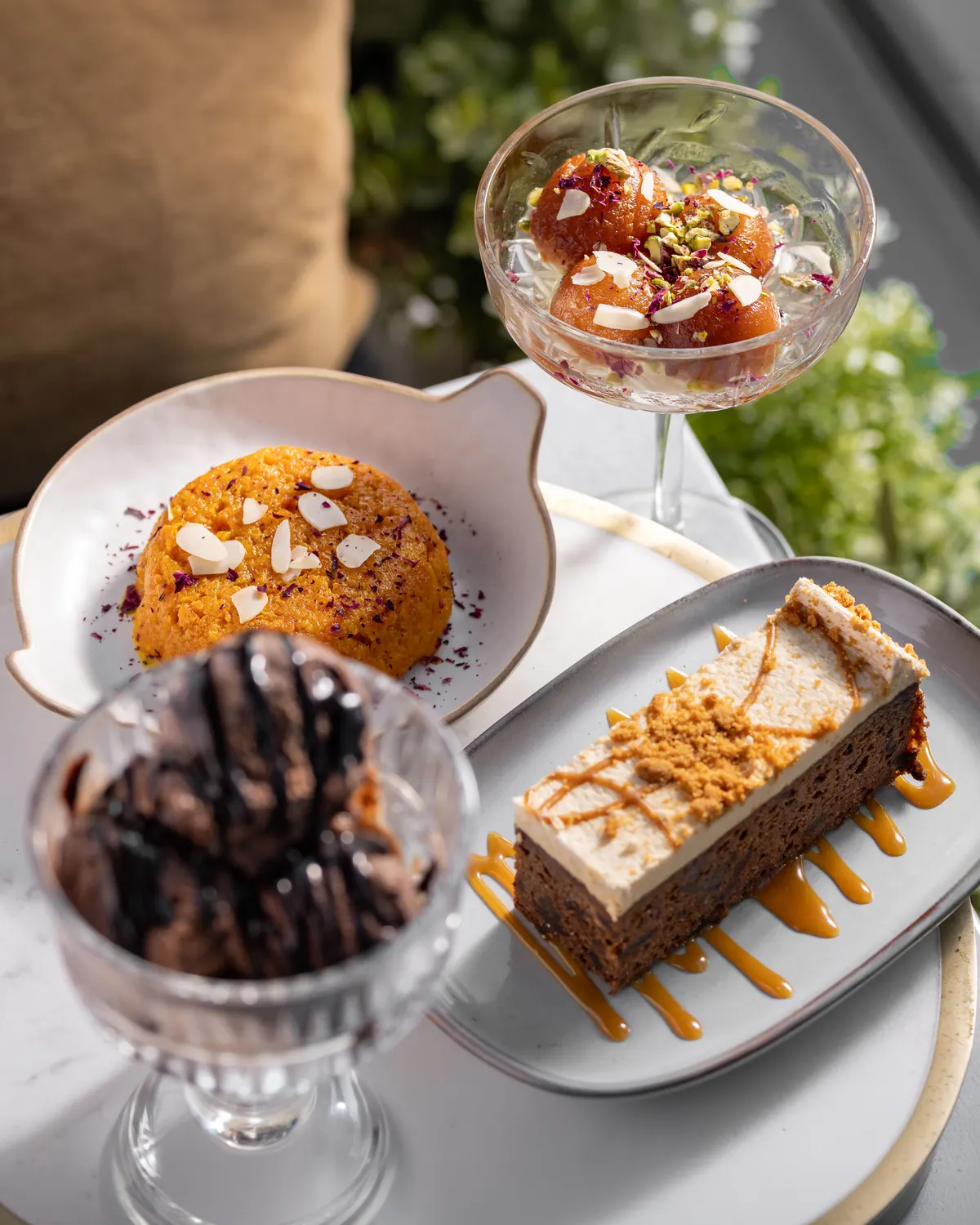 Padharo desserts: gajar halwa, gulab jamun in a coupe glass, a chocolate sundae and a caramel-topped slice