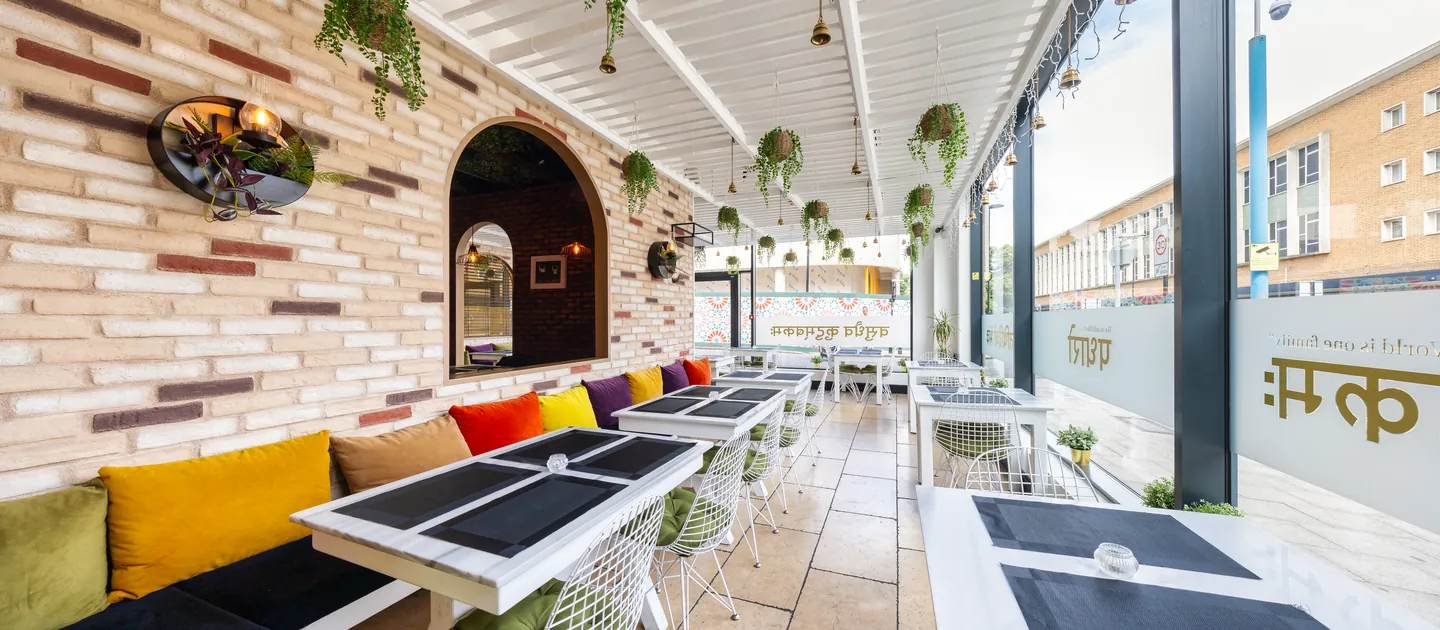 Padharo's covered terrace: hanging plants, colourful cushioned seating and exposed brick, seen from the East Street entrance